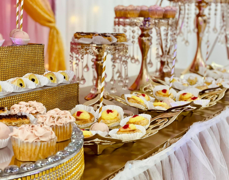 Mesa de postres artesanales sobre bases doradas para primera comunión